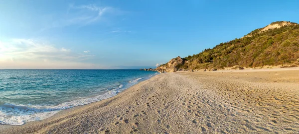 Yunanistan 'daki Lefkada adasının yeşil kayalıklarıyla sıcak yaz mevsiminde gün batımı manzaralı Megali Petra kumlu plajı. İyon Denizi 'ne yaz yolculuğu