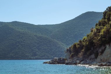 Yunanistan 'ın Lefkada adasındaki güneşli kayalık kayalıklar, yeşil tepeler ve berrak mavi sular. Yaz vahşi doğa İyon Denizi 'ne seyahat eder. Renk sınıflandırılmış