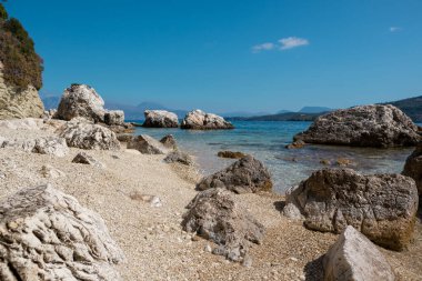 Yunanistan 'ın Lefkada adasının açık deniz kıyısında kumsalda beyaz çakıl taşları ve kayalar. Yaz vahşi doğa seyahati İyon Denizi 'ne