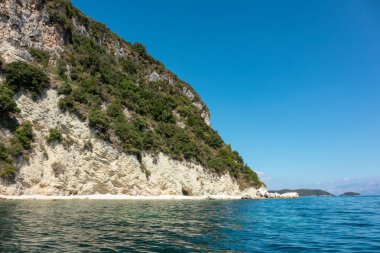 İyon Denizi 'nin mavi sularında yeşil kayalıkları ve parlak gökyüzü olan beyaz çakıl taşı sahili. Yunanistan 'daki Lefkada adasının doğası. Yaz seyahati