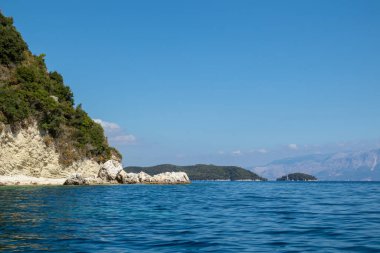İyon Denizi 'nin mavi sularındaki yeşil uçurumları ve parlak gökyüzü olan kayalık sahiller. Yunanistan 'daki Lefkada adasının doğası. Yaz tatilinde gidilecek yer
