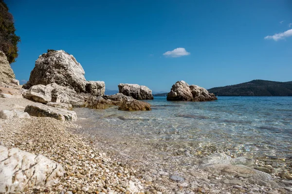 Beyaz çakıl taşları ve kayalar, Yunanistan 'ın Lefkada adasının açık deniz kıyısında deniz mavisi ile yakın çekim yapıyorlar. İyon Denizi 'ne yaz canlı doğa yolculuğu
