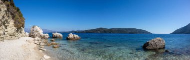 Yunanistan 'ın Lefkada adasının açık deniz kıyısında beyaz çakıl taşları ve kayalık plajlardan oluşan geniş bir manzara. Yaz vahşi doğa seyahati İyon Denizi 'ne
