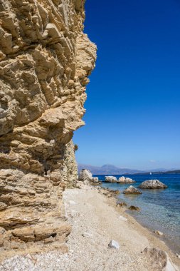 Yunanistan 'ın Lefkada adasının kıyısındaki gök mavisi berrak su ve dağlarla dolu çakıl taşlı sahildeki kayalık kayalıklar. Yazın İyon Denizi 'ne vahşi doğa yolculuğu