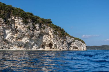 Kayalık beyaz uçurumları ve parlak gökyüzü olan İyon Denizi 'nin mavi yansıtıcı suyu. Yunanistan 'daki Lefkada adasının doğası. Yaz tatilinde gidilecek yer
