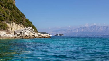 Manzaralı mavi kayalar, kayalıkları ve parlak gökyüzü olan İyon Denizi 'nin berrak ve berrak sularını dalgalandırdı. Yunanistan 'daki Lefkada adasının doğası. Yaz tatilinde gidilecek yer