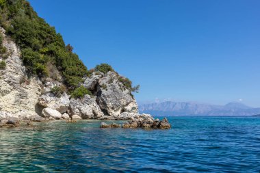 Manzara kayalıkları ve parlak gökyüzüyle İyon Denizi 'nin berrak, berrak mavi sularında kayalar. Ormos Desimi 'nin Doğası, Lefkada Adası, Yunanistan. Yaz tatili