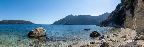 Yunanistan 'ın Lefkada adasında kayalık uçurumları ve masmavi berrak suları olan geniş beyaz çakıl taşları sahili manzarası. Yaz vahşi doğa seyahati İyon Denizi 'ne
