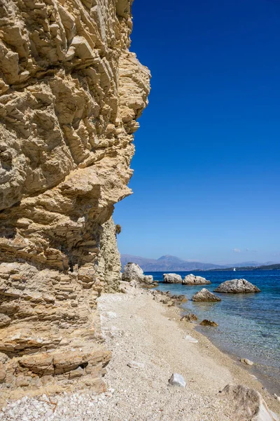 Yunanistan 'ın Lefkada adasının kıyısındaki gök mavisi berrak su ve dağlarla dolu çakıl taşlı sahildeki kayalık kayalıklar. Yazın İyon Denizi 'ne vahşi doğa yolculuğu