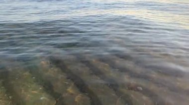 Sakin deniz dalgaları dalgalı kum tabanının üzerinde yavaşça yansıyor.