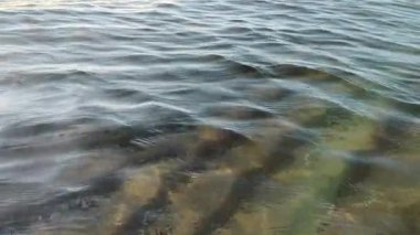 Kum tabanı üzerinde deniz dalgalarını temizle ve yavaş çekimde ışık yansımaları oluştur.