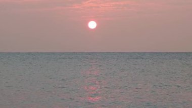 Rahatlatıcı sabah deniz manzarası, ufukta güneş ve sakin deniz dalgaları.