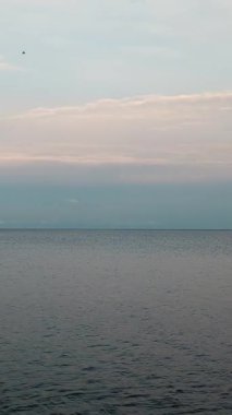 Bir deniz yüzeyinde dikey çekim. Akşam gökyüzünün altında sakin su