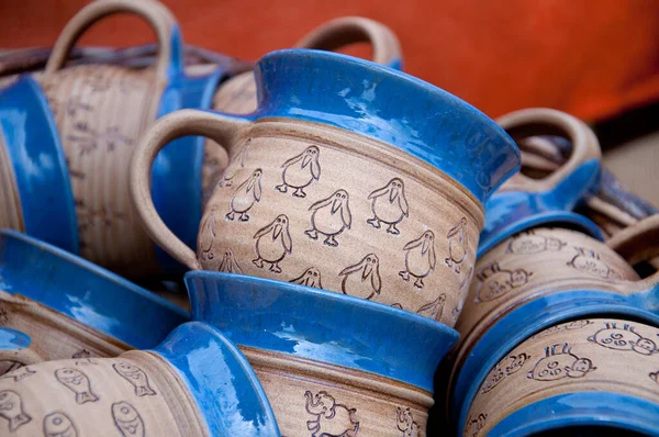 Handmade painted blue-brown mugs made of ceramic clay. Animal motifs - penguins, sheep, fish, elephants. Traditional craft.