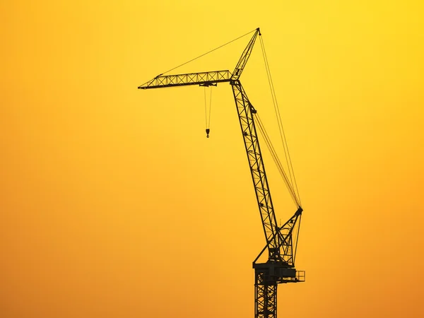 Silueta de la grúa de construcción en el cielo del atardecer — Foto de Stock