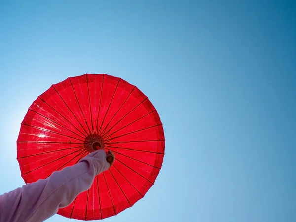 Ombrello sulla mano della donna contro il sole cielo blu — Foto Stock