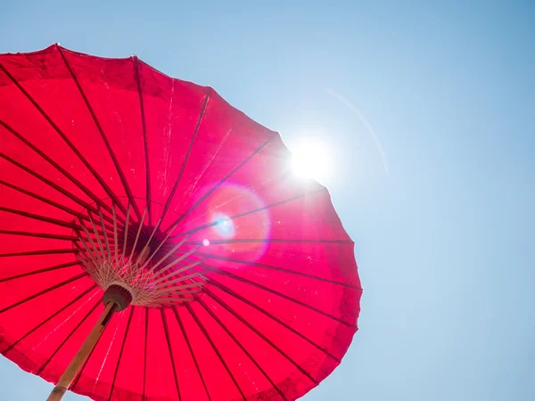 Guarda-chuva de papel vermelho contra o céu ensolarado — Fotografia de Stock