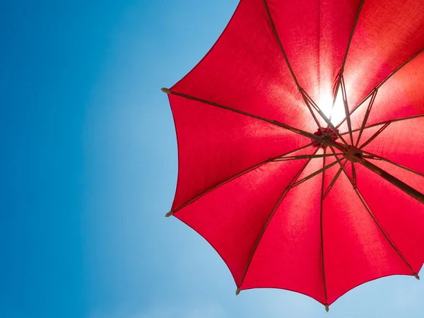 Guarda-chuva vermelho no céu azul ensolarado — Fotografia de Stock