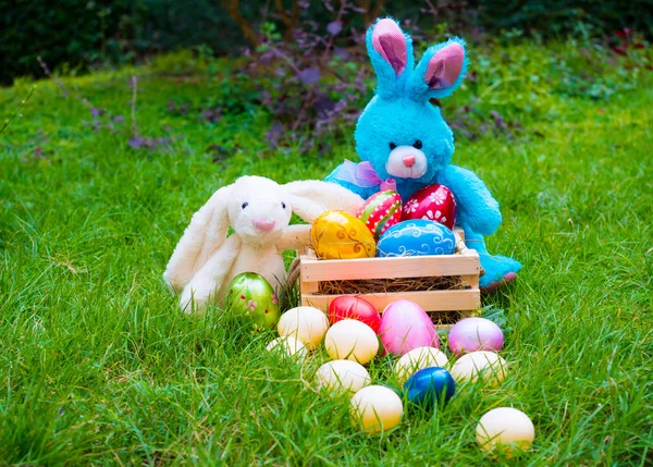 Colorful easter eggs on a grass with two bunnies — Stock Photo, Image