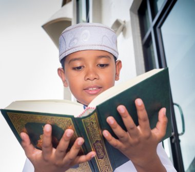 Asian muslim child with smile face reads the holy Quran clipart