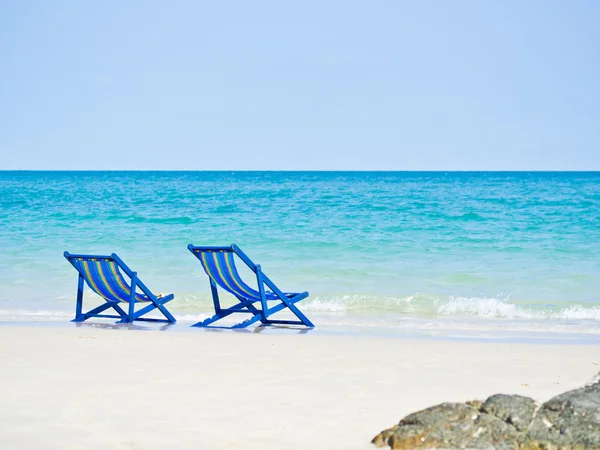 Два пляжных шезлонга на берегу перед синим морем и волной — стоковое фото