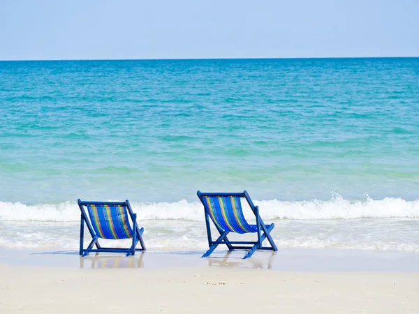 İki sandalye mavi deniz ve dalga önünde sahilde plaj