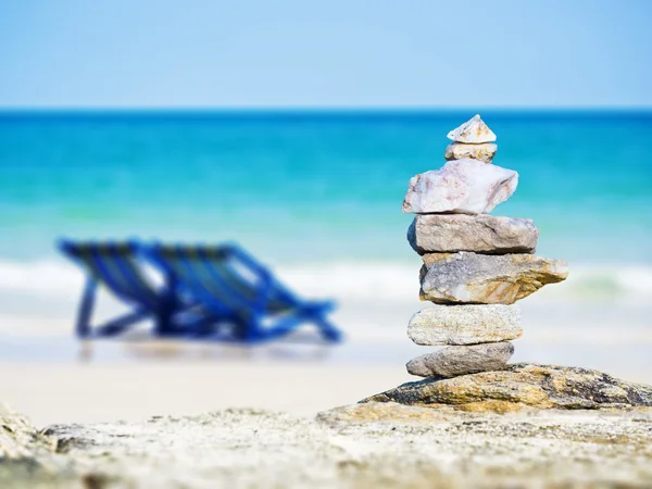 Stenarna balans på solstolar på stranden framför blå havet och våg — Stockfoto