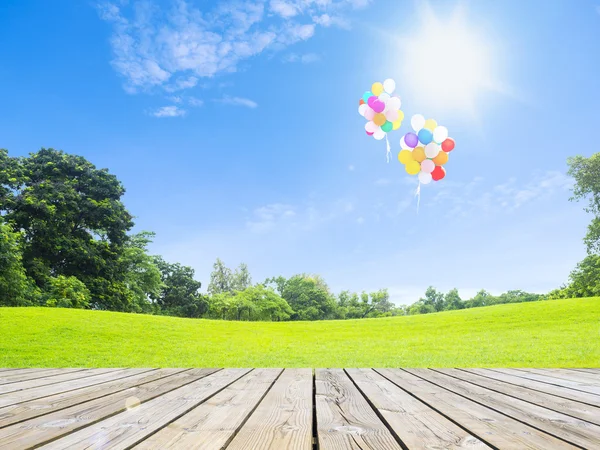 Ballons over wooden floor and green grass — Stock Photo, Image