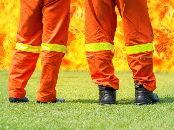 Bombeiros em pé na frente de uma grande chama — Fotografia de Stock