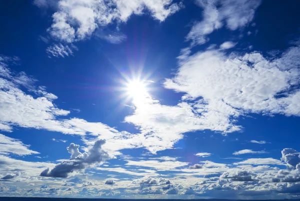 Zon flare omgeven door de prachtige helder blauwe hemel — Stockfoto