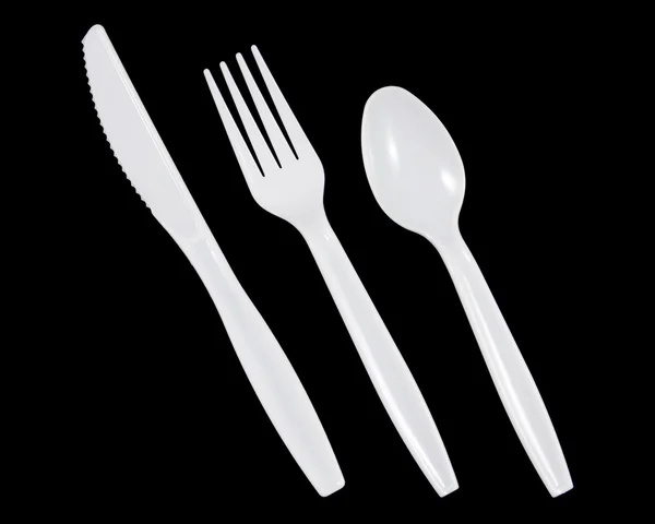 Λευκό πλαστικό μαχαίρι, πιρούνι και κουτάλι σε μαύρο φόντο. — Φωτογραφία Αρχείου