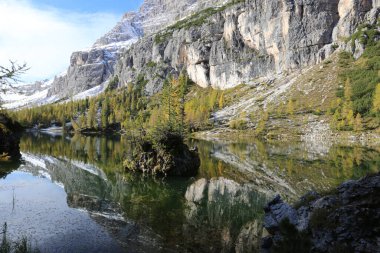 Dolomitlerde sonbahar, dağlarla çevrili Federa gölü manzarası.
