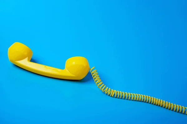 Žlutý retro telefon přijímač na modrém pozadí. — Stock fotografie