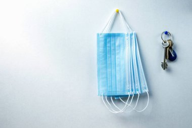 Mavi tıbbi koruyucu maskeler ve beyaz bir duvara karşı bir sürü anahtar. Evden ayrılırken koronavirüsten korunma kavramı.
