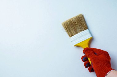 Beyaz arka planda izole edilmiş boya fırçası olan kırmızı bir iş eldiveni verin. Yenileme konsepti