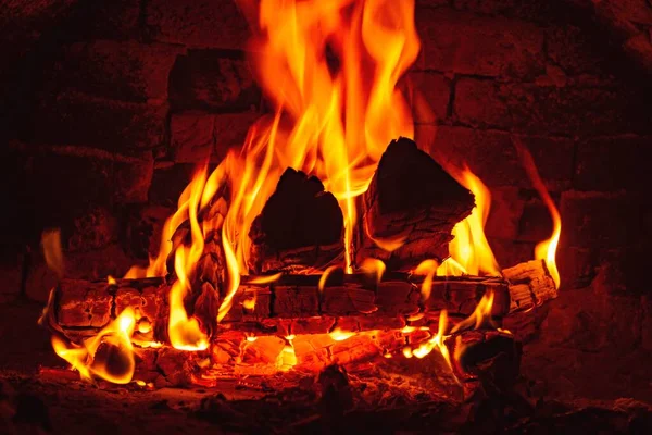 Background with burning firewood in a brick fireplace. Warmth and comfort