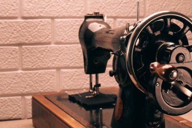 Beyaz tuğla duvara karşı ahşap bir masası olan eski dikiş makinesi. Klasik stil