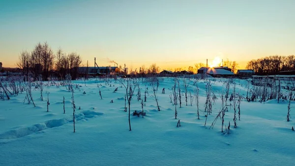 Winter landscape with the setting sun over the snow-capped rooftops. Evening time