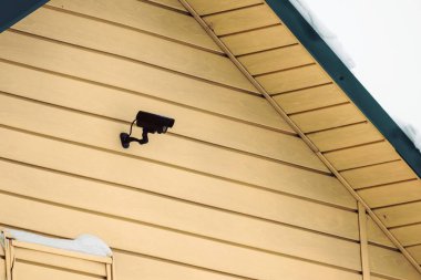 Bir kır evinin duvarındaki siyah güvenlik kamerası. Emlak güvenliği kavramı