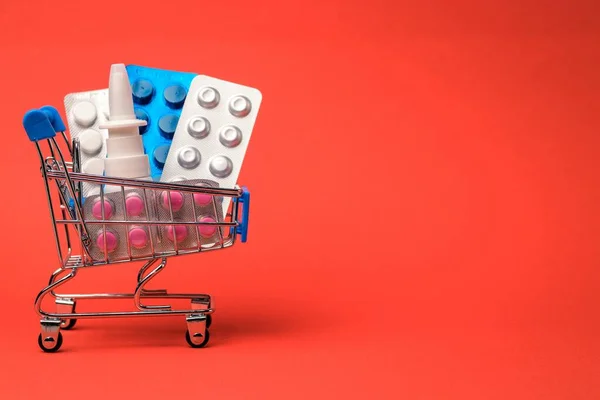 Shopping cart with medications on a bright orange background. Close-up. Pharmacy sale