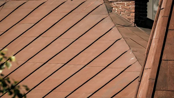 View of the metal rusty roof of the roof of an old house with a brick chimney. — Stock Photo, Image