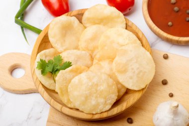 Bol yağda kızartılmış Puri Luchi soslu raita. Bir beyaz tabak.