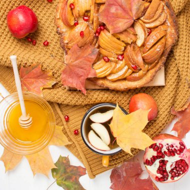 Elmalı turta, sonbahar yemeği, rahat süveter ve sonbahar yapraklı bir kupa içinde çay, bal, elma ve nar