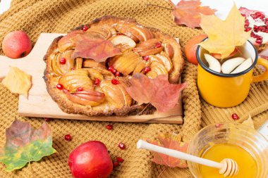 Elmalı turta, sonbahar yemeği, rahat süveter ve sonbahar yapraklı bir kupa içinde çay, bal, elma ve nar