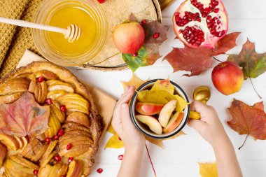 Sonbahar elmalı turta, yazı için yer, eller sonbahar çayı, nar ve bal ile bir kupayı tutar.