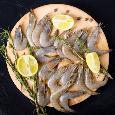 Çiğ, limonlu kaplan karidesi. Deniz ürünleri. Üst Manzara. Siyah bir arka planda. Boş kopyalama alanı.