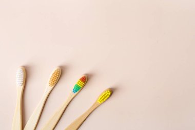 Bej arka planda bambu rengi diş fırçası ve diş macunu tutan kadın görüntüsü. Bej arkaplanda bambu diş fırçaları