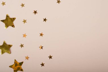 Yıldızlı bej arkaplan. Altın yıldız kahveli şampanya şişesi ve bej renkli pastel arka planda köknar dalları. Tatil, parti ve kutlama konsepti. Kopyalama alanı olan yaratıcı düz.