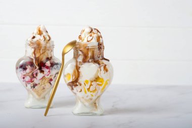 Çikolata soslu vişneli dondurma ve koyu arkaplanda kurumuş gül çiçeği. Aşk, Sevgililer Günü konsepti. Sevgililer günü için kavanozda dondurma.