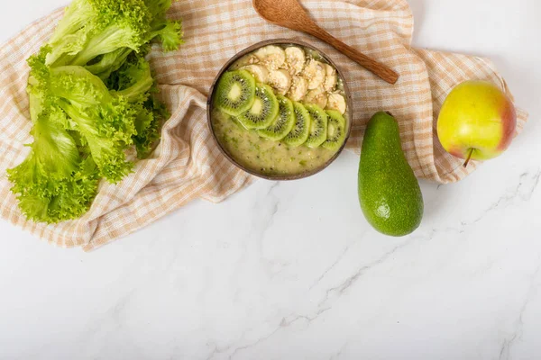 banana, avocado and kiwi smoothie in coconut bowl. Green smoothie bowl with avocado, kale and chia seeds